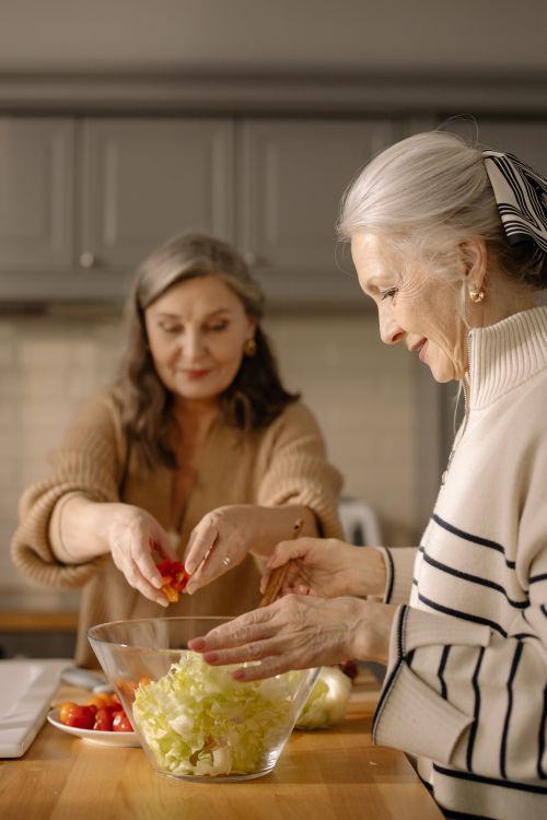 Two older women preparing food.