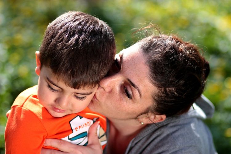 A mother kissing her son