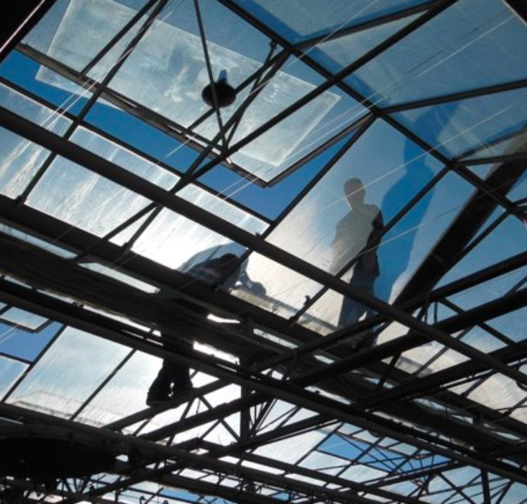 Workers on the roof of a greenhouse building.
