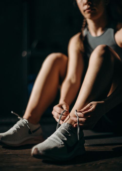 A woman lacing up a set of sneakers.