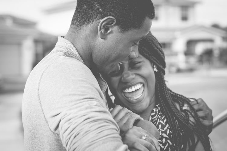 A man and woman laughing and hugging.