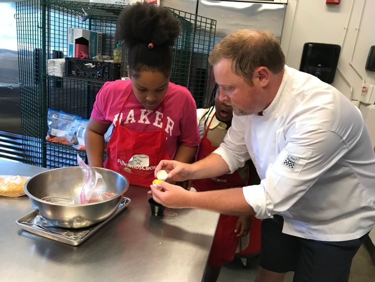 Child with Chef teaching to separate an egg white and yolk