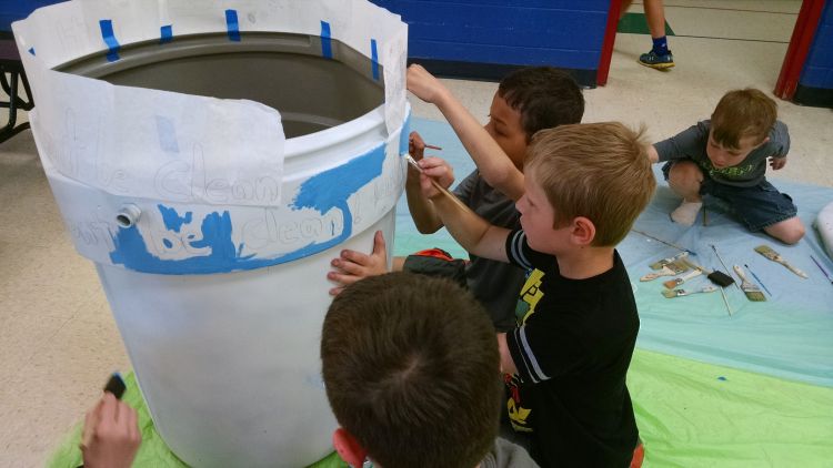 Youth paint a rain barrel recently. Sketching your design first on a sheet of paper can help the painting process. The rain barrels will be on display around Bay County in August. Photo: Michigan Sea Grant