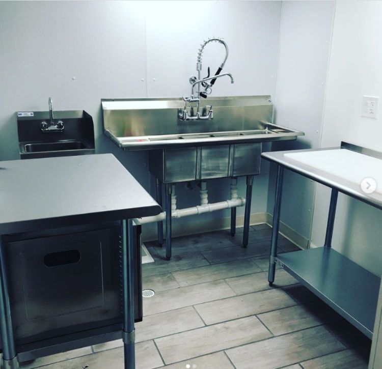 A stainless steel kitchen sink with prep table