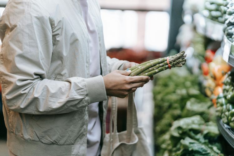 A man picking up asparagus at the super market.
