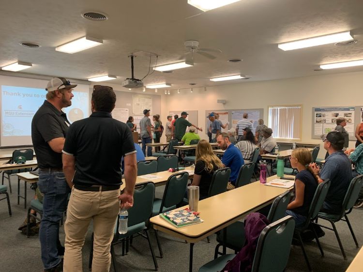 Adults standing around in a classroom.