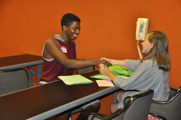 Two youth shaking hands in a mock interview.