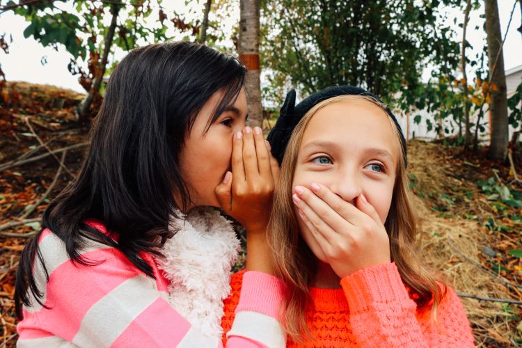 Girl telling a secret to another girl