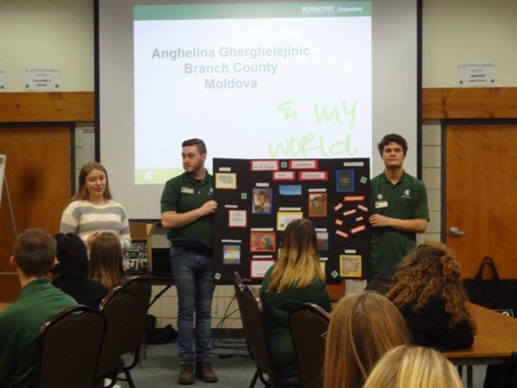Three young adult participants in from the Michigan 4-H Youth Leadership & Global Citizenship Spectacular presenting in front of their peers.