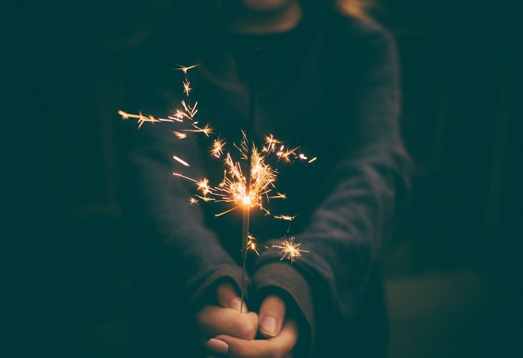 A hand holding a sparkler in the dark.