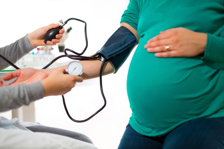 A pregnant woman getting blood pressure checked by a doctor.