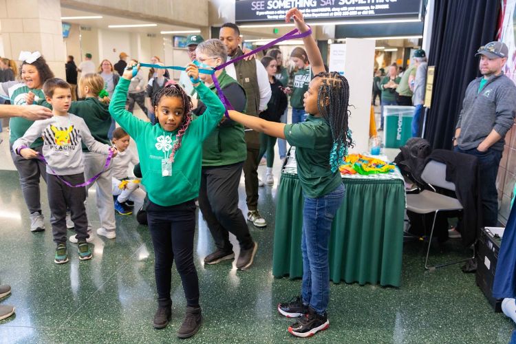 Young children in 4-H attire doing an hands-on activity.