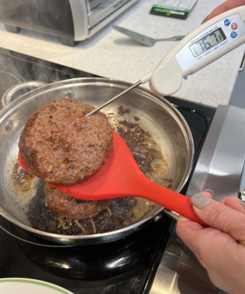 Someone taking the temperature of a plant-based burger.