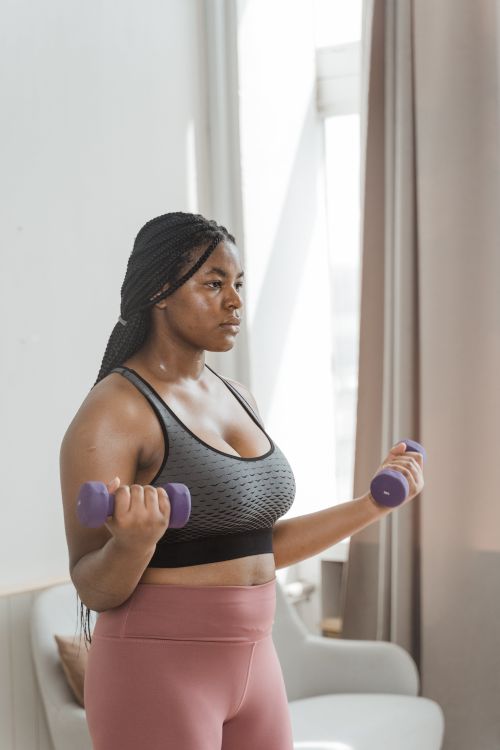 A young woman exercising indoors with small free weights.