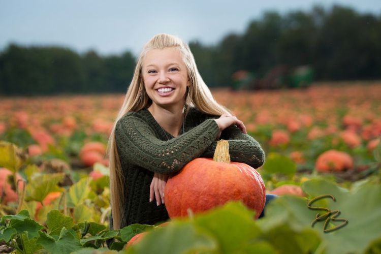 Kenna Schwass smiles in a pumpkin field