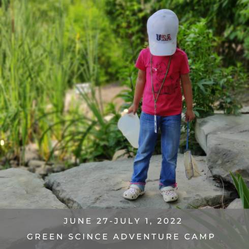 Camper standing near pond with net and bucket with a caption that says Green Science Adventure Camp.
