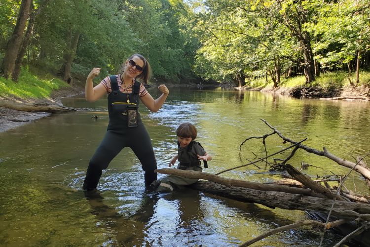 Rebecca Jordan stands in a river in waders next to her son