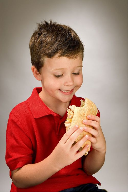 Child in red polo eating sandwich