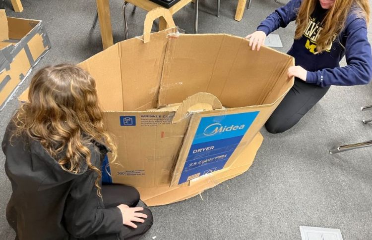 Youth building a cardboard sled.