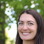 Megan McManus smiles in front of a wooded background