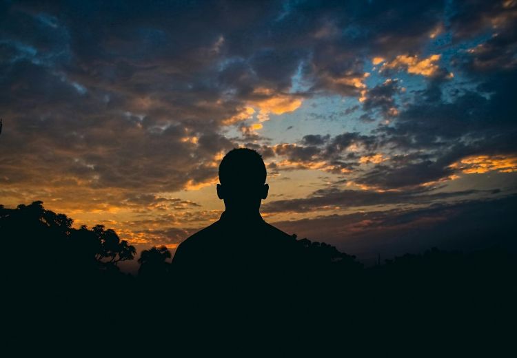 A person standing and watching a sunset.