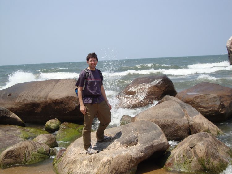 Mark Axelrod stands on a large rock near the shore of a large body of water