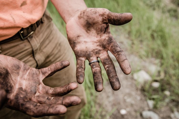 A man's hands covered in dirt and filth.