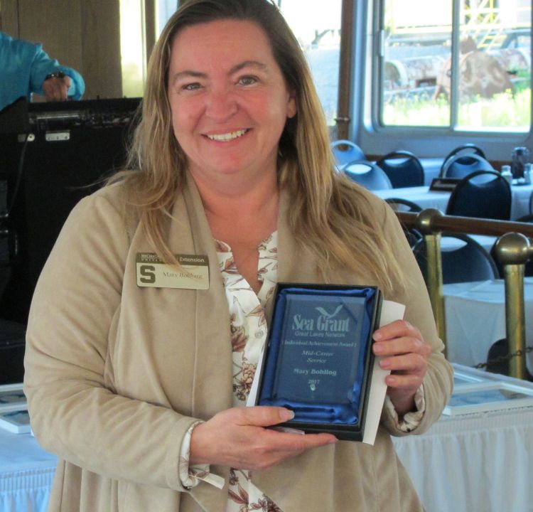 Mary Bohling receives the Great Lakes Sea Grant Network’s mid-career award. Below: Brandon Schroeder receives a Distinguished Service Award. Todd Marsee (left) and Mark Breederland accept the project award on behalf of Michigan Sea Grant.