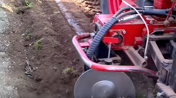 red hop mower going across brown dirt