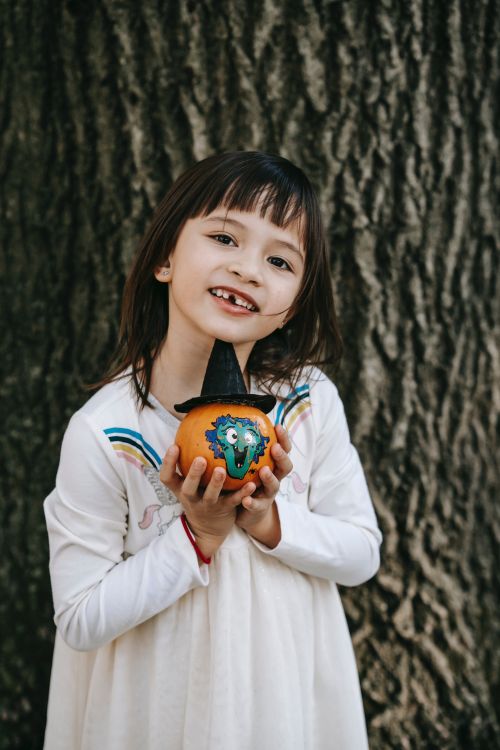 A child holding a decorated Halloween pumpkin.
