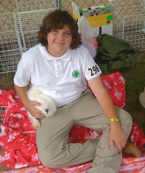 Boy sitting with chicken at fair