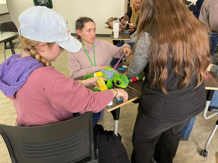 Youth wrapping bandage around a stuffed animal.