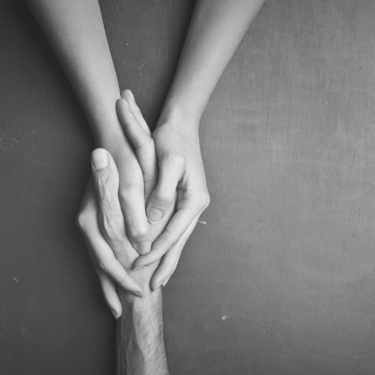 Two hands clasped together in a black and white background.