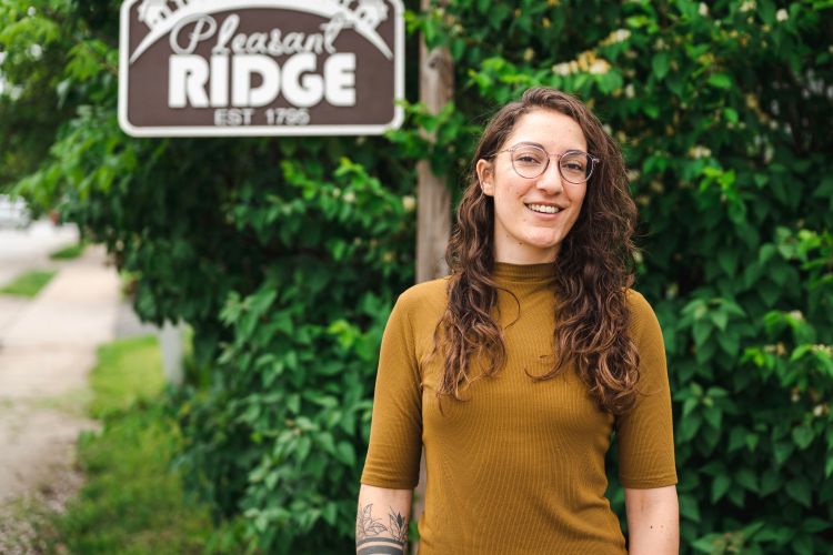 Kate Gille stands in front of a sign for Pleasant Ridge neighborhood in Cincinnati, Ohio