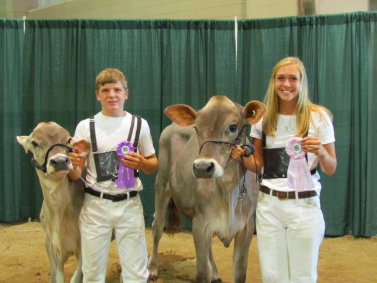 Stoney Buell (left) and Kristen Burkhardt (right) stand with their champion heifers after the Brown Swiss show during the 2016 Michigan 4-H Youth Dairy Days. Photo: Sara Long.