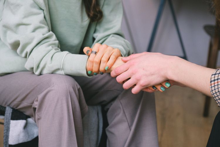 A person comforting another by holding their hands.