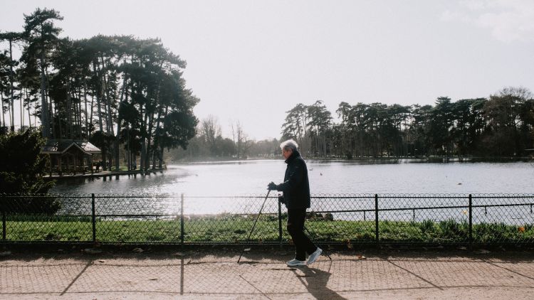 A woman walking outside by a river.