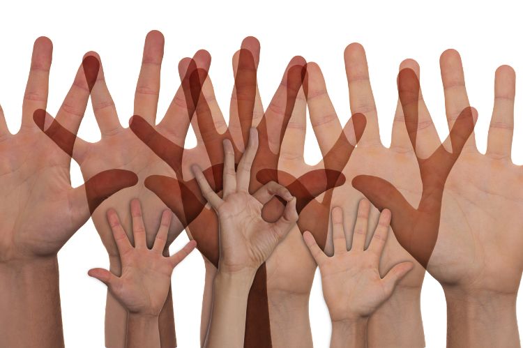 Numerous outreached hands reaching up to the sky.