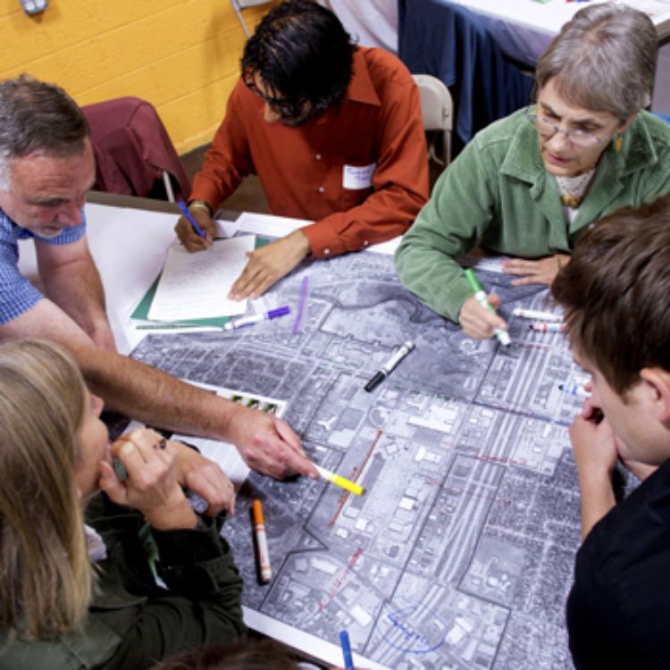 A group of men and women work together on a project during a charrette.