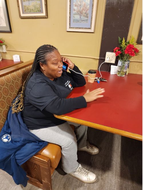 Marquetta Frost talks on the phone while sitting in a booth at a restaurant