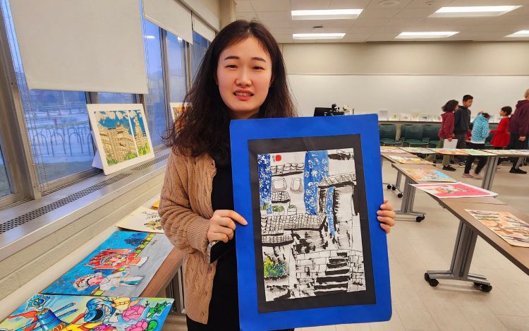 A Chinese girl holding up a piece of art.