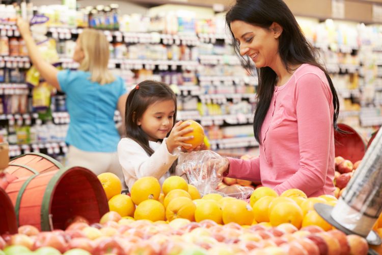 A child and her mother choosing healthy snack options at the grocery store.