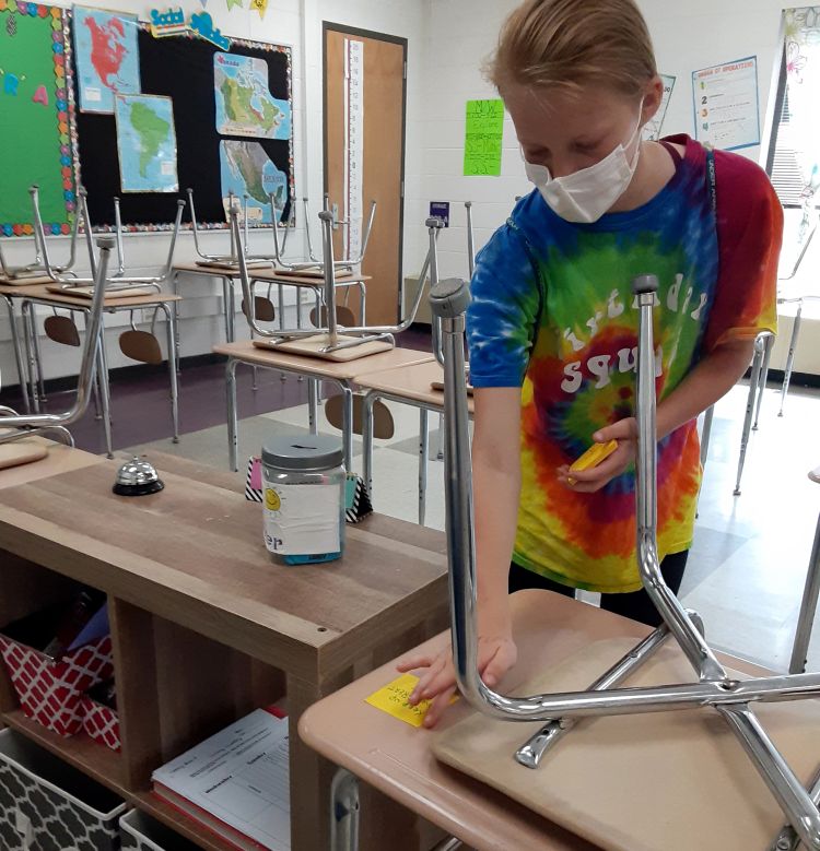 A girl placing a post-it note on a desk.