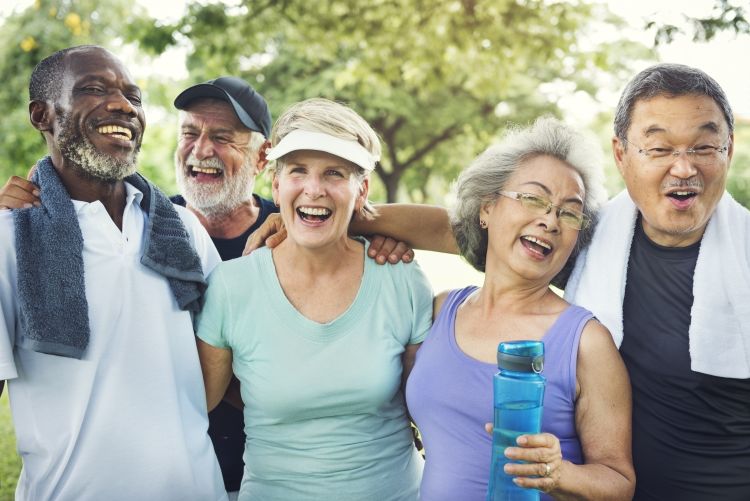 A group of older adults laughing and exercising outdoors.