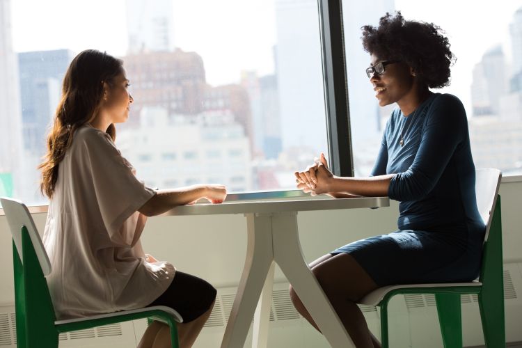 Two individuals sitting across from each other at a table engaged in a conversation.