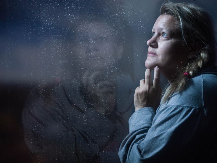 A woman staring mindfully out a window.