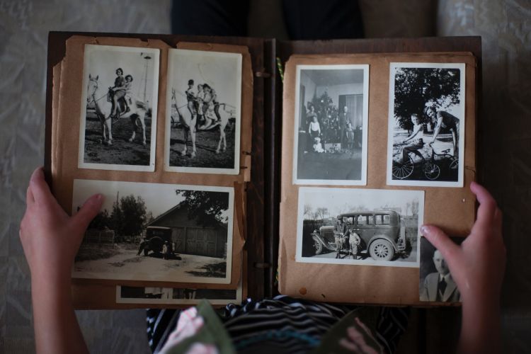 Person holding old photo book with grayscale pictures.