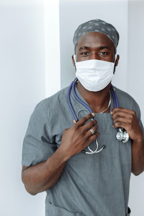 A young doctor in scrubs and a mask.
