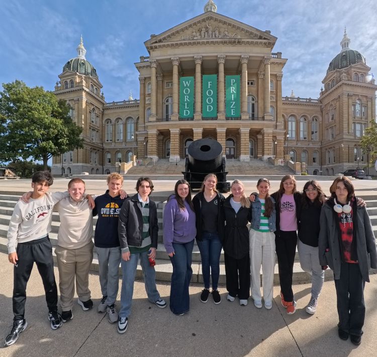 A group of smiling kids outside an old decorative building.