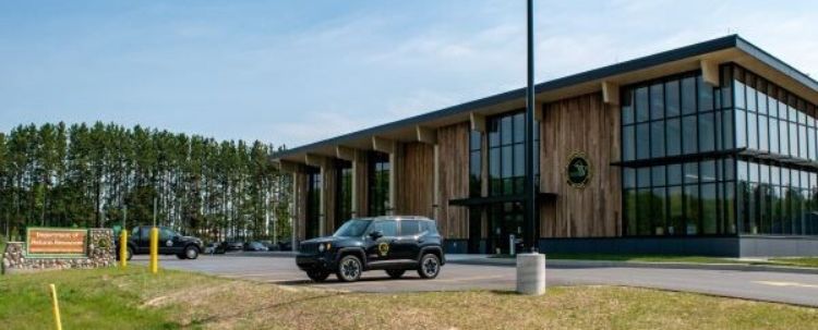 Exterior shot of the MDNR Newberry Customer Service center with a car parked in the front parking lot with trees in the background.